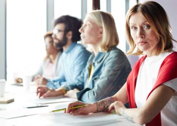 Donna con tatuaggi durante una riunione di lavoro